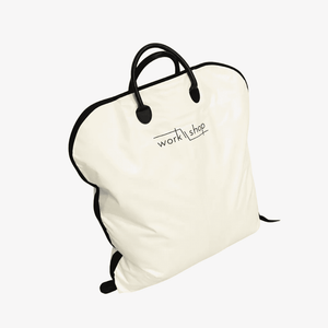 An off-white garment bag with black handles, black piping, and a black 'workshop' logo printed on the front, shown against a plain white background.
