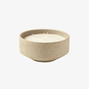 A round, speckled ceramic candle holder containing white wax with multiple wicks, set against a plain white background.